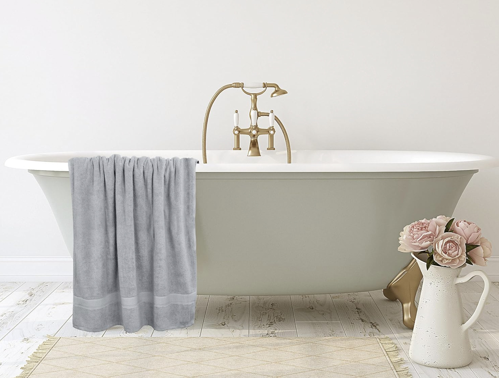 A grey bath towel hanging over a white bathtub in a calm, spa-like bathroom
